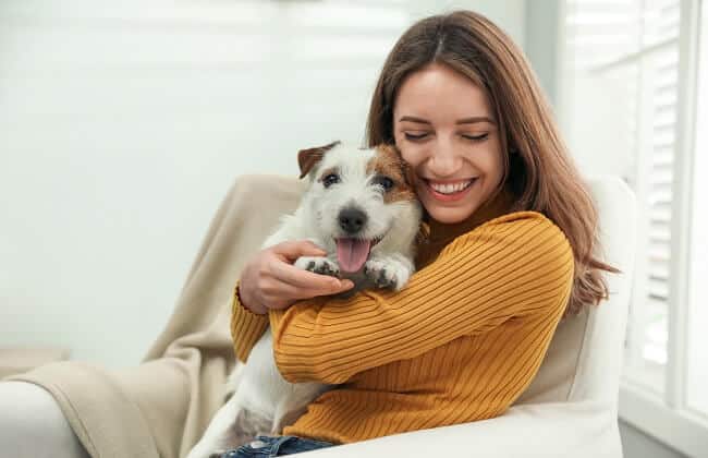 A smiling dog owner hugs her dog, both looking content and flea-free.